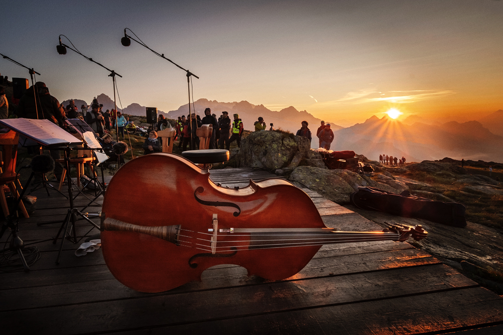Il violoncello di Dario Brunello in primo piano e sullo sfondo un'alba sulle Dolomiti